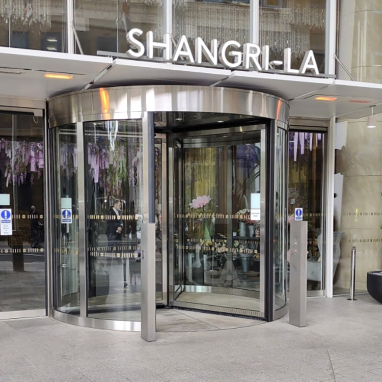 Revolving glass door at entrance to hotel with chrome finish