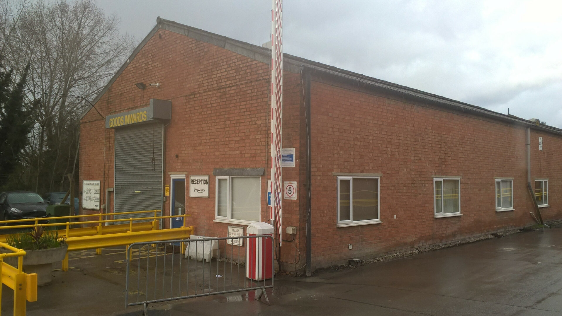Space saving installation of rising boom barriers on the corner of a warehouse