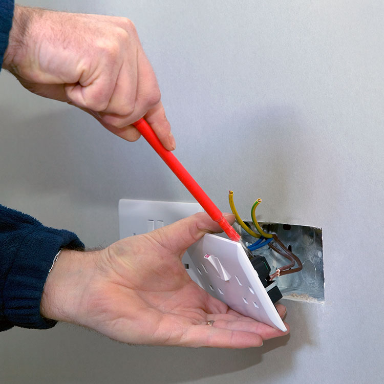 Electrician installing a plug socket in a wall