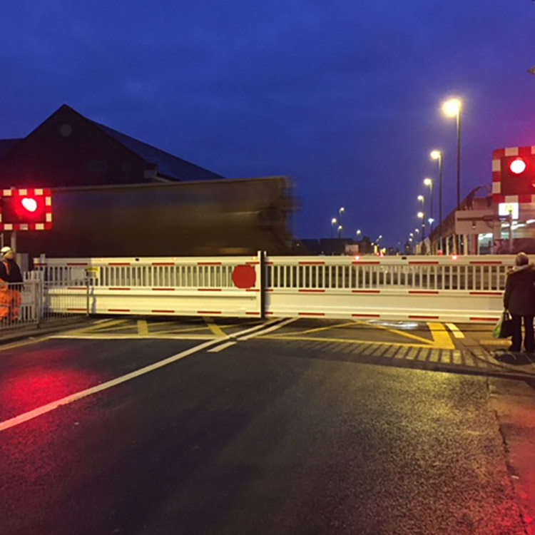 Railway level crossing with lights flashing at night